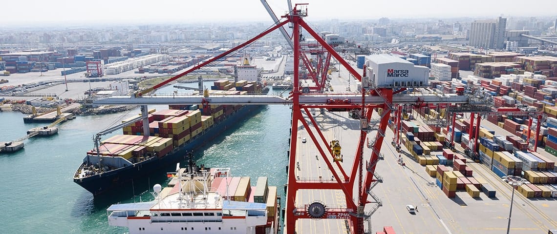 Vue aérienne d’un port chargé de conteneurs et de navires de fret à quai.