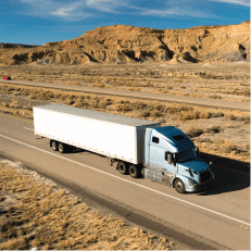 Camion de fret sur une autoroute désertique, représentant le transport routier longue distance.